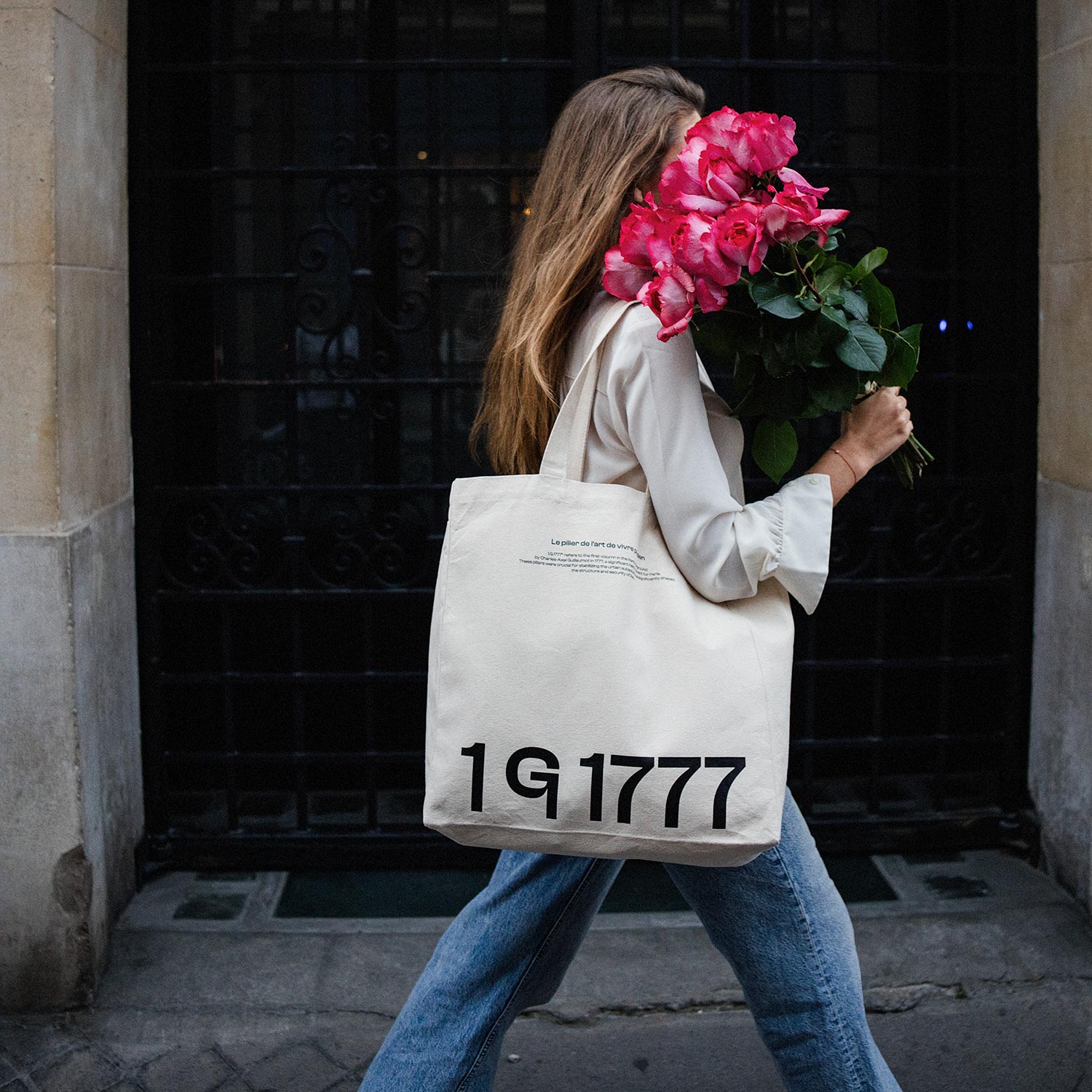 Model walking with the 1G1777 canvas tote bag by Rosenstaub, with pink flowers covering her face