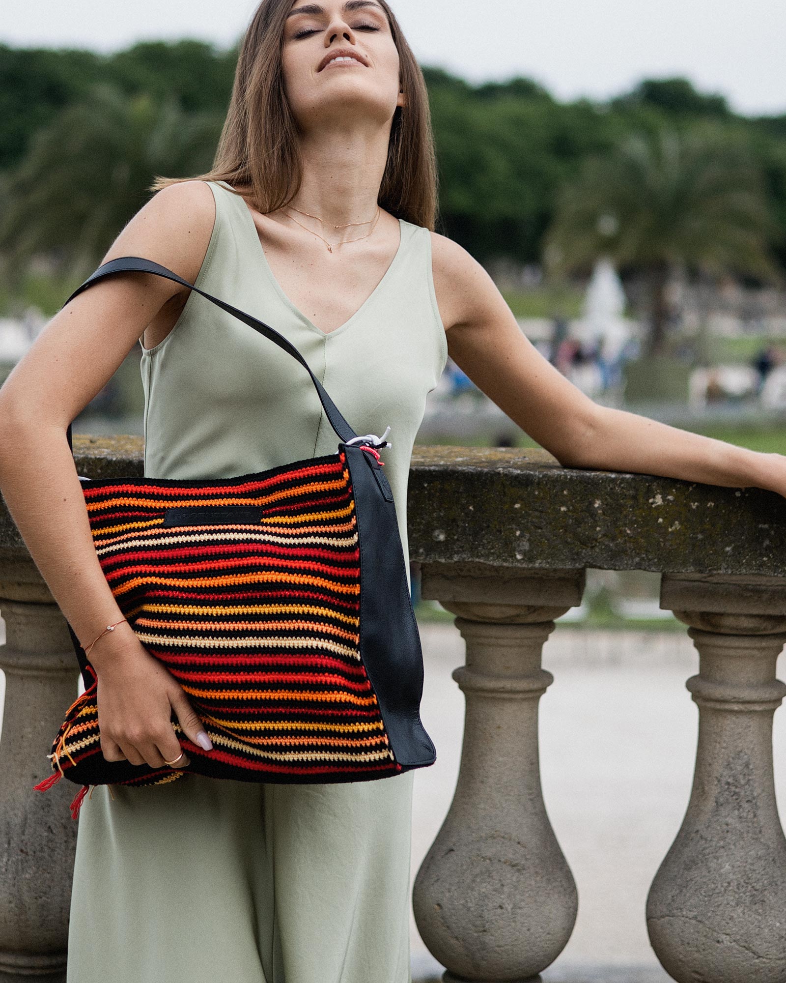 Model wearing the Rosenstaub Crochet Shopper No. 29 of 30 in a park, featuring colors red, orange, and yellow